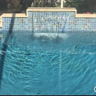 A person jumping in the water from a pool.