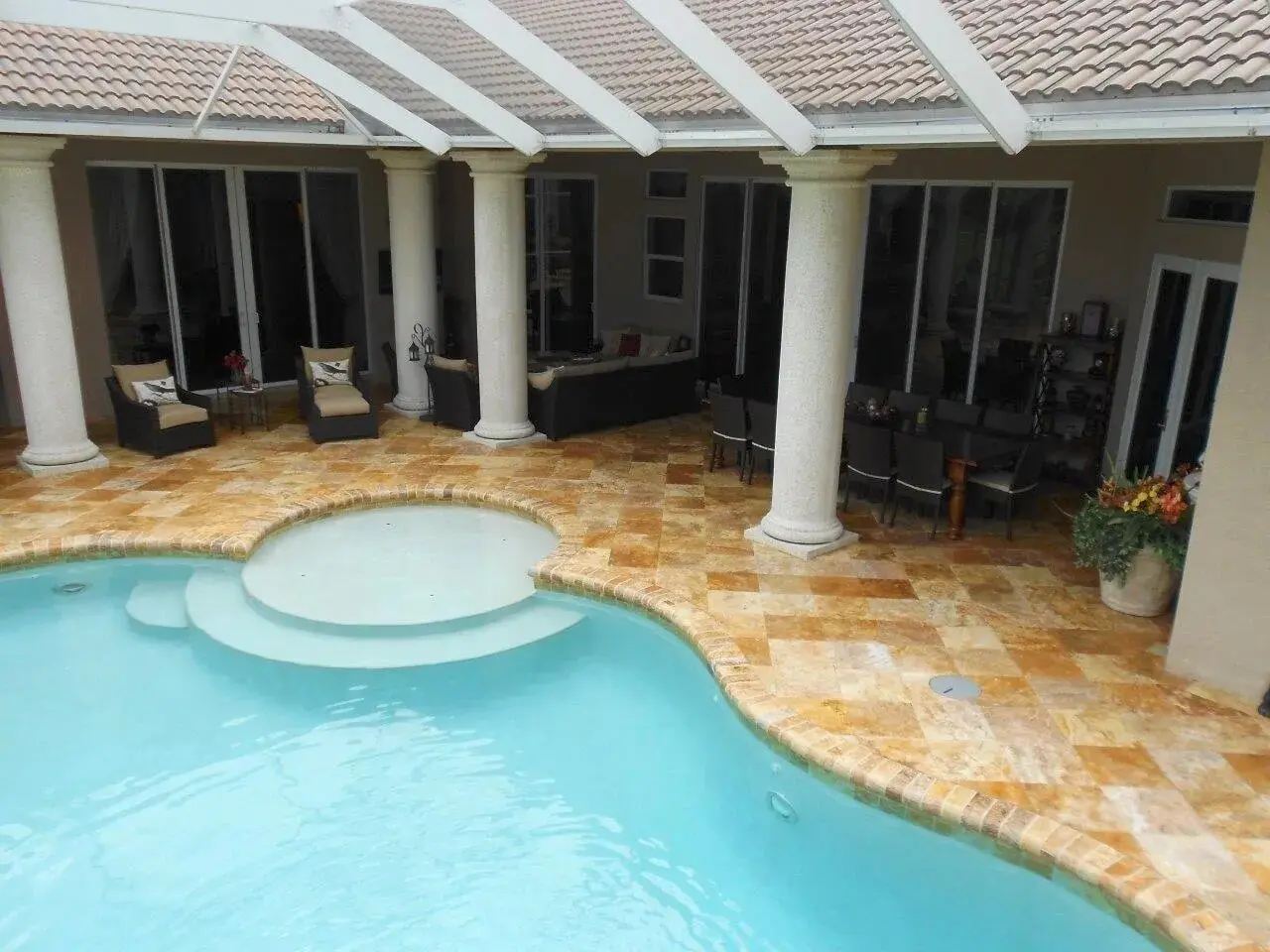 A pool with a large patio area and a stone wall.