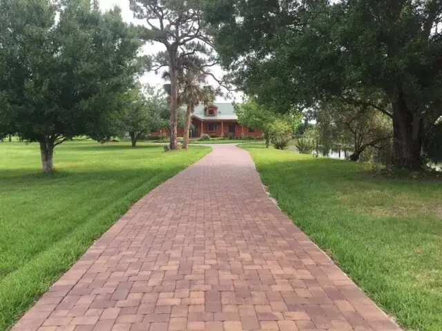 A brick path leading to a house in the distance.