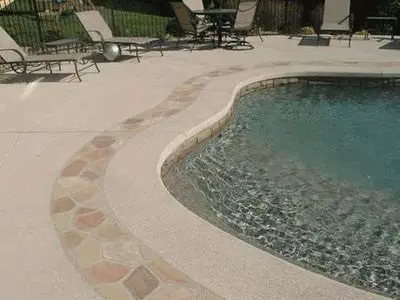 A pool with a stone walkway around it.